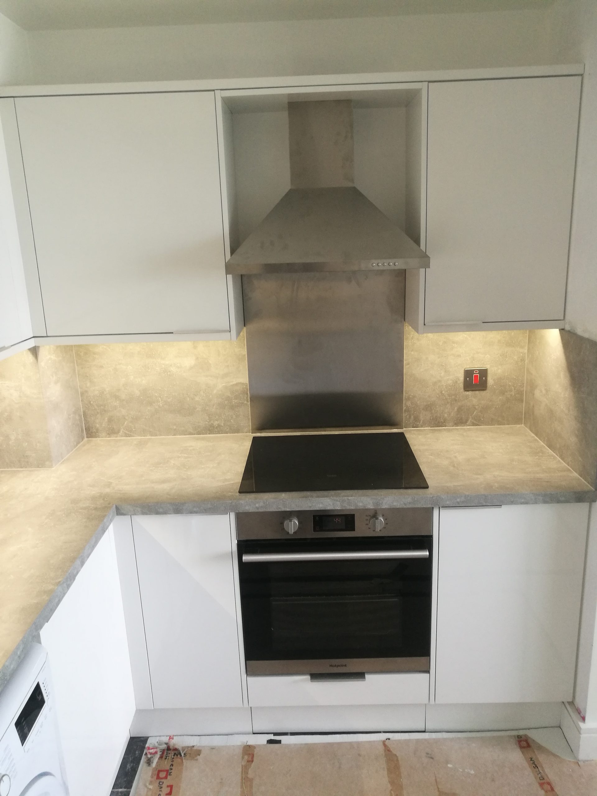 Fitted kitchen with new appliances and tiled splashback